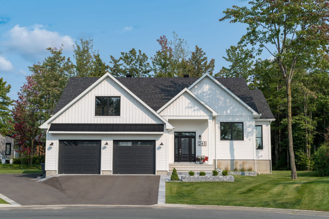 Grande maison unifamiliale blanche avec toit gris sur un vaste terrain